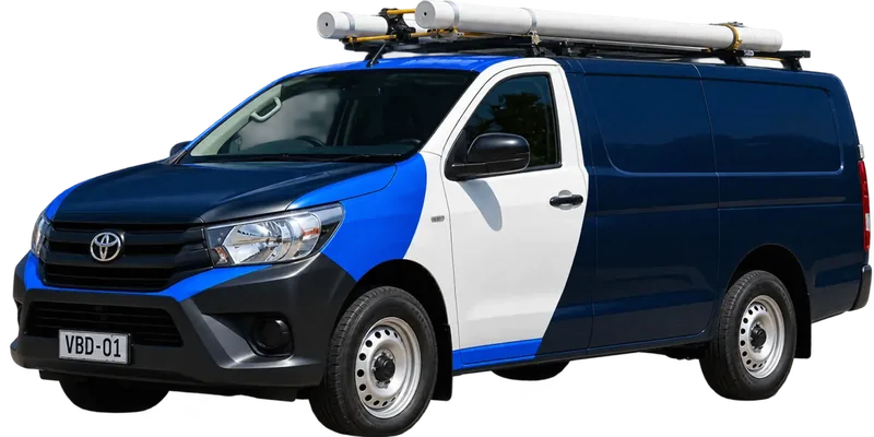 A licensed Queens Park plumbing van loaded with pipe on the roof rack